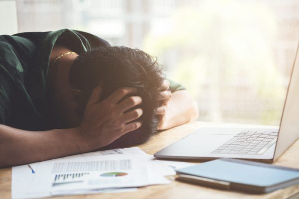 Burnout Syndrome, Man sleeping at his desk working over a laptop,Tried overworked, Freelance man working overload, Young business owner at home office,man feel tried and nap on desk.