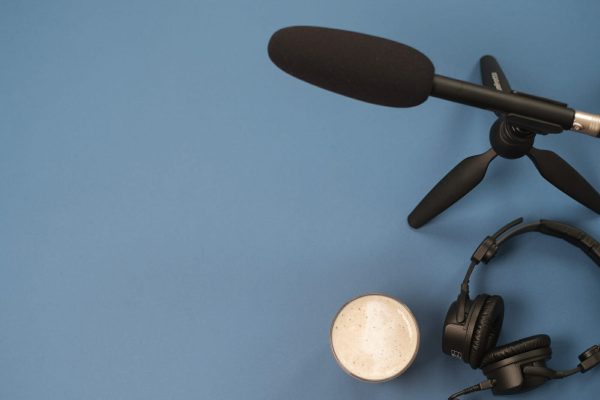 Flat lay composition with Headphones, microphone and coffee on a yellow background. Podcast or webinar concept.
